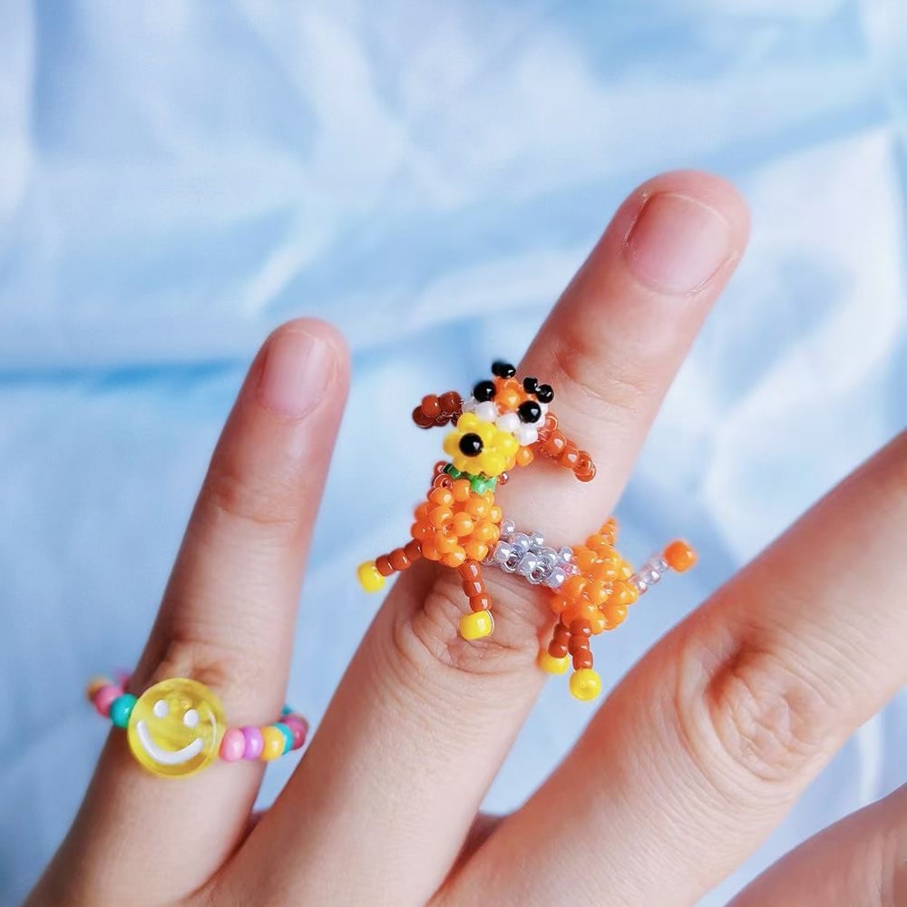 Colorful beaded dog ring on a finger with a blurred blue background