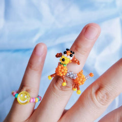 Colorful beaded dog ring on a finger with a blurred blue background
