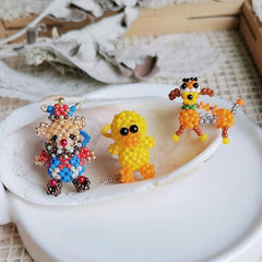 Three colorful beaded animal figurine rings on a shell