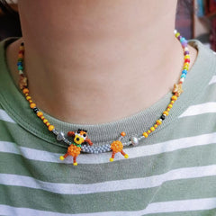 Colorful beaded necklace with cartoon character pendant on a person wearing a green and white striped shirt.