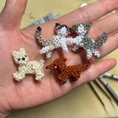 Hand holding four beaded dog figurines of different colors on a light background - verhalo custom jewelry