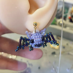 Close-up of a beaded spider earring on an ear with a blurred background  - Verhalo custom jewely