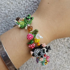 Colorful beaded garden bracelet on a wrist with a textured background  - Verhalo Custom Jewelry