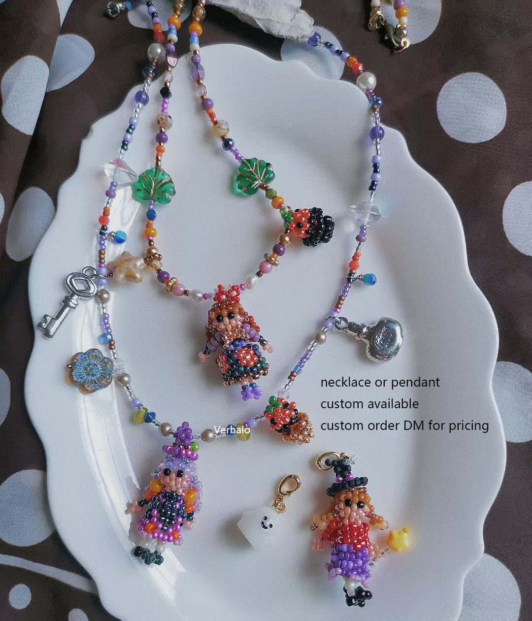 Colorful beaded necklace with magic girl pendants on a white dish.- verhalo custom jewelry