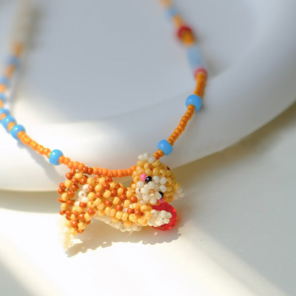 Beaded necklace with a dcat-shaped pendant on a white background