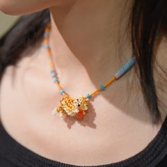 Necklace with a colorful cat pendant worn by a person