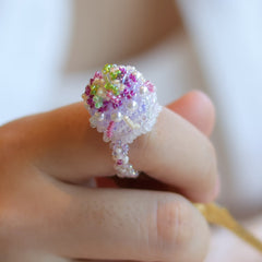 Colorful beaded cake ring on a finger with a blurred background