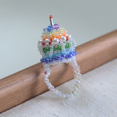 Colorful beaded cupcake ring on a wooden stick with a neutral background