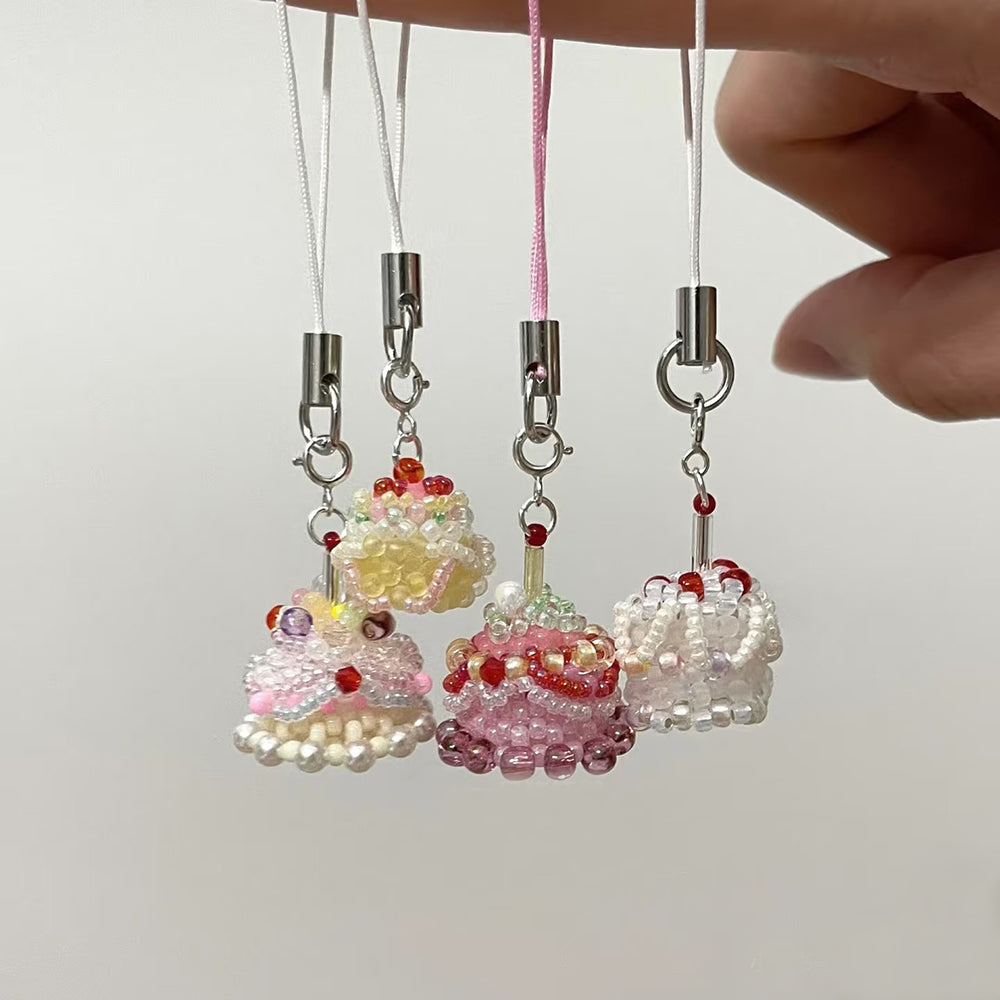 Four beaded birthday cake charms  on strings against a light background.
