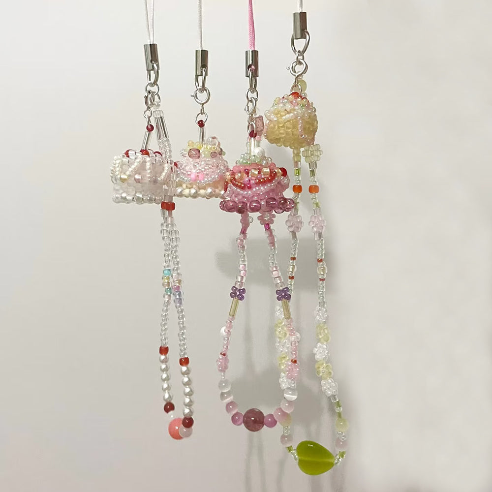 Decorative string with colorful beads and cake charms on a white background