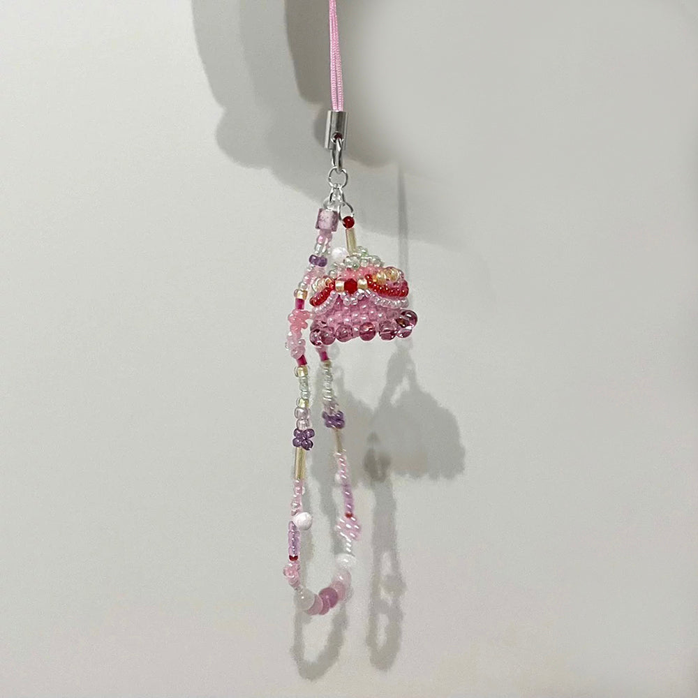 Decorative phone charm with beads and a cake on a white background