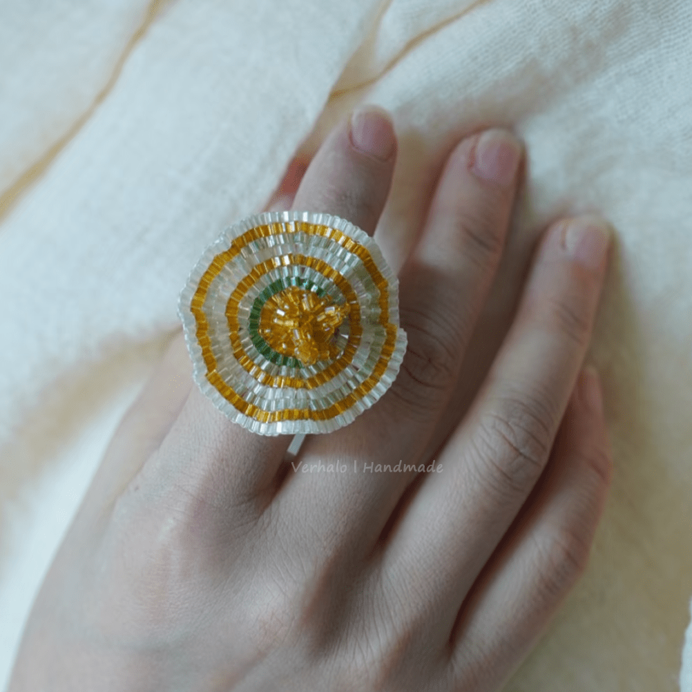 Decorative ring with beaded design on a hand against a light background