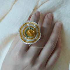 Decorative ring with beaded design on a hand against a light background