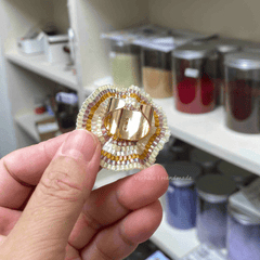 Hand holding a beaded ring with a blurred background