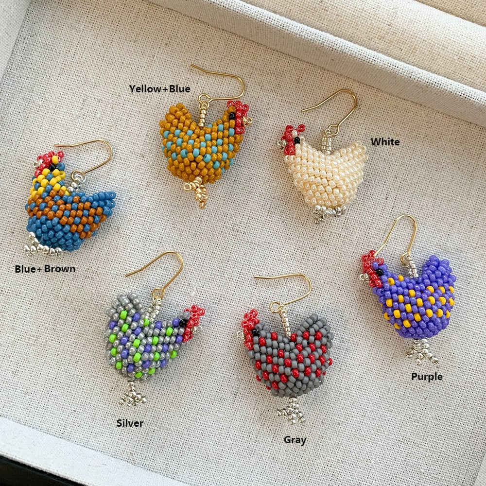 Colorful beaded chicken-shaped earrings on a textured surface