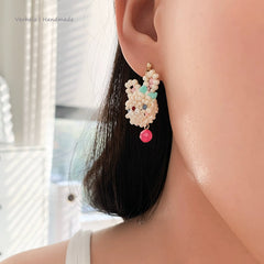 Close-up of a person wearing rabbit beaded earrings with a blurred background