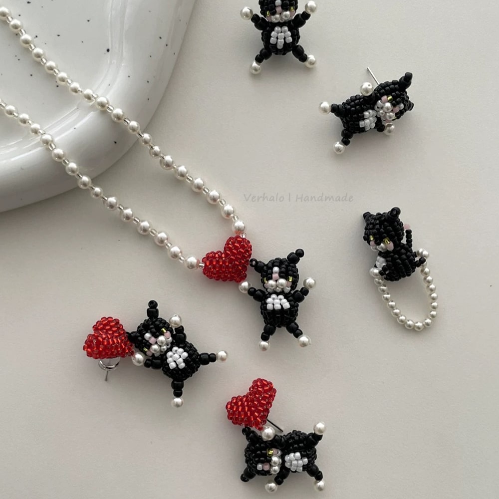 Beaded black and white cat figurines with red hearts on a white surface.