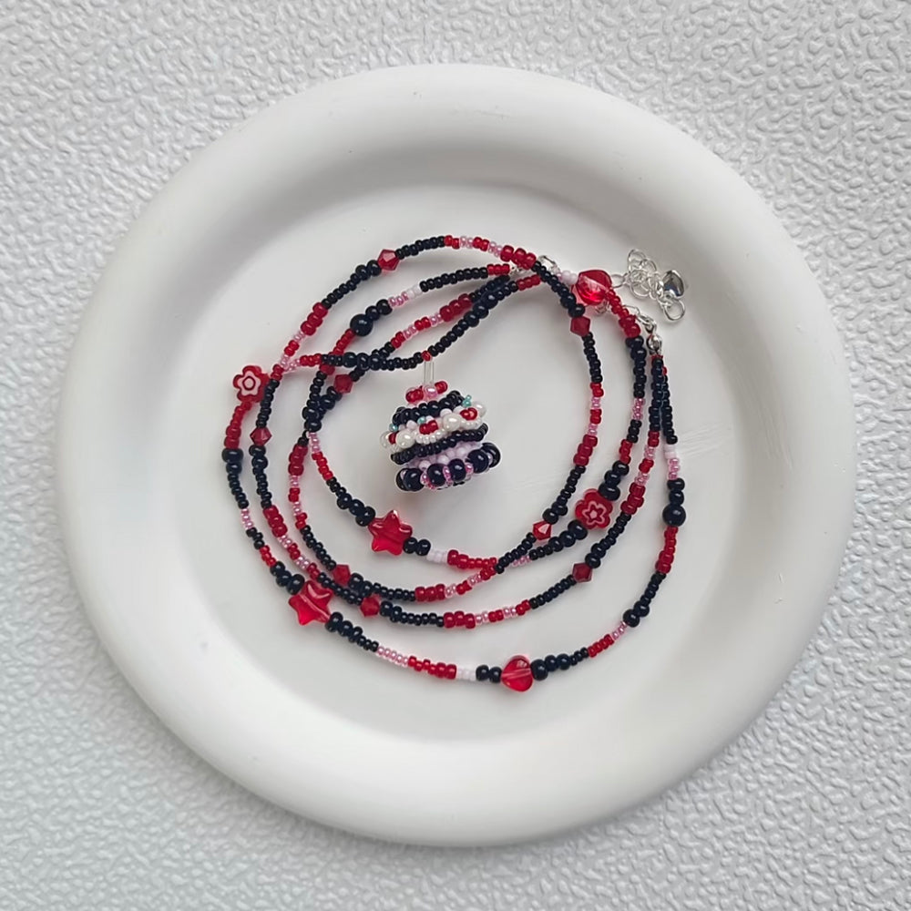 blackberry cake Beaded necklace set on a white plate with a textured background