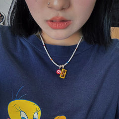 Person wearing a blue sweater with a cartoon character and a necklace with colorful pendants.