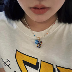 Person wearing a necklace with colorful  M&M's pendant on a white shirt with yellow text