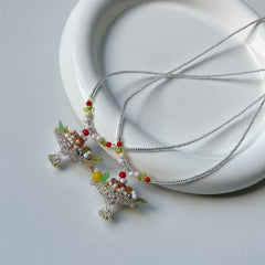 Necklace with colorful beads and pudding boat cake charms on a white background