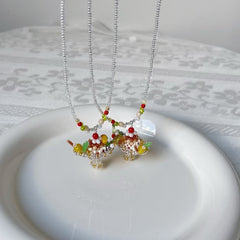 Two necklaces with colorful pudding boat cake pendant on a white plate