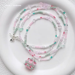 Beaded necklace with a birthday cake pendant on a white surface