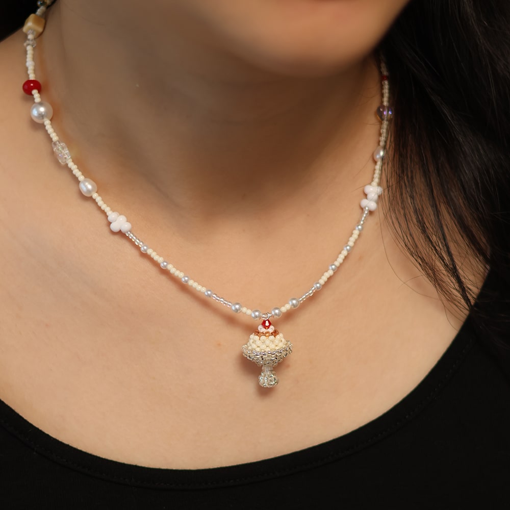 Pearl necklace with a decorative pendant on a person wearing a black top.