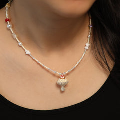 Pearl necklace with a decorative pendant on a person wearing a black top.