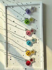Colorful emoji & star necklaces on a display board with a white background