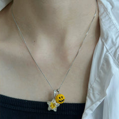 Necklace with a emoji & star pendant featuring a smile face on a person wearing a white shirt.