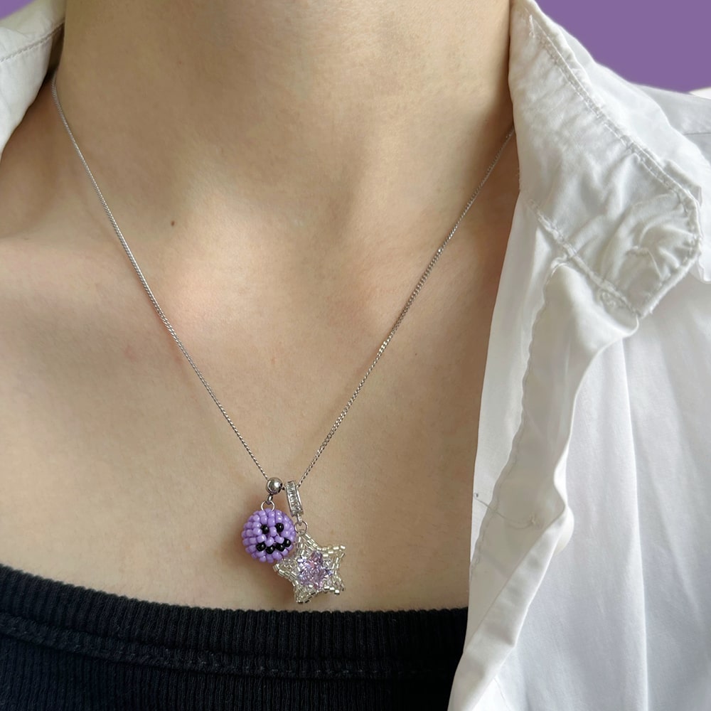 Necklace with a star-shaped pendant worn by a person against a white shirt and black top background.