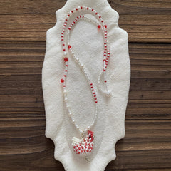Beaded necklace with red and white chcicken pendant on a white fabric background - Verhalo Jewelry