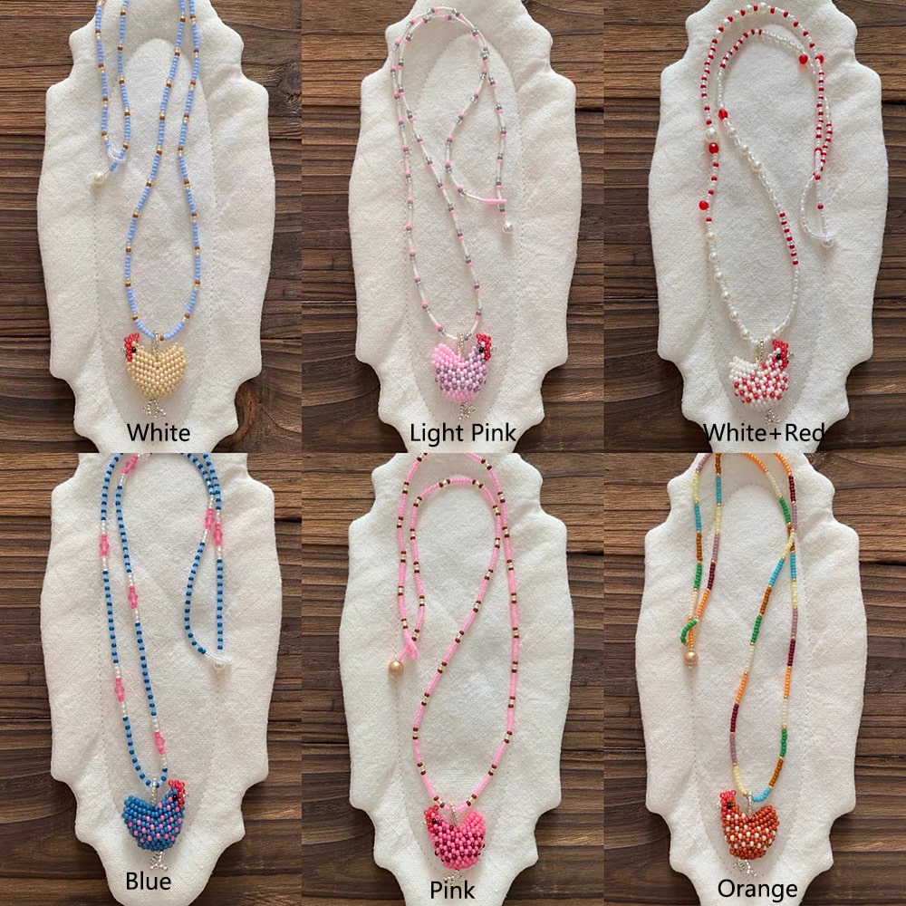 Set of beaded chicken necklaces on white stands with color labels on a wooden surface - Verhalo Jewelry