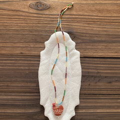Necklace with orange chicken on a white stone surface against a wooden background - Verhalo Jewelry