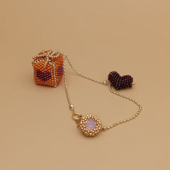 Beaded gift box bag charm with a decorative clasp on a beige background