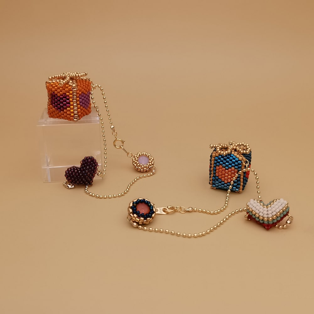 Set of beaded gift box bag charms on a beige background