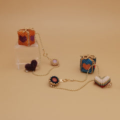 Set of beaded gift box bag charms on a beige background