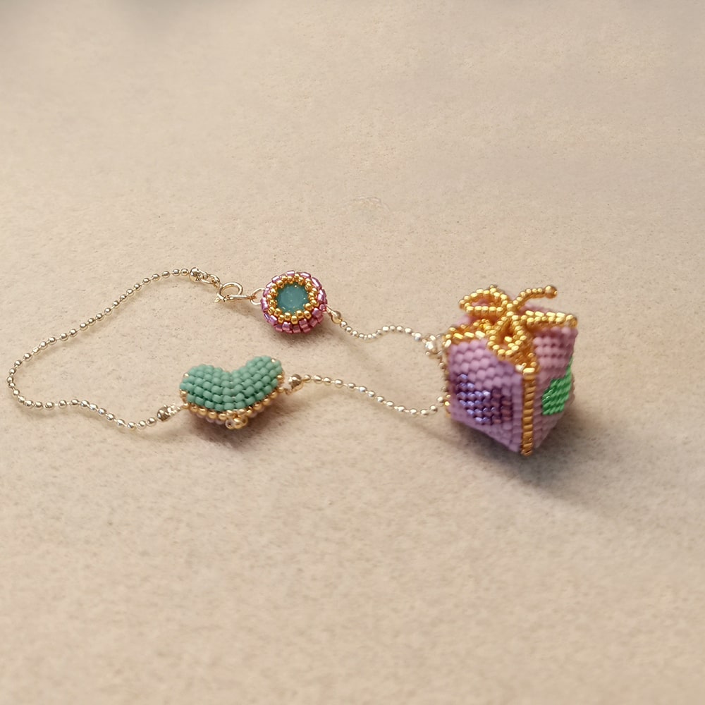 pink beaded gift box bag charm  on a beige background
