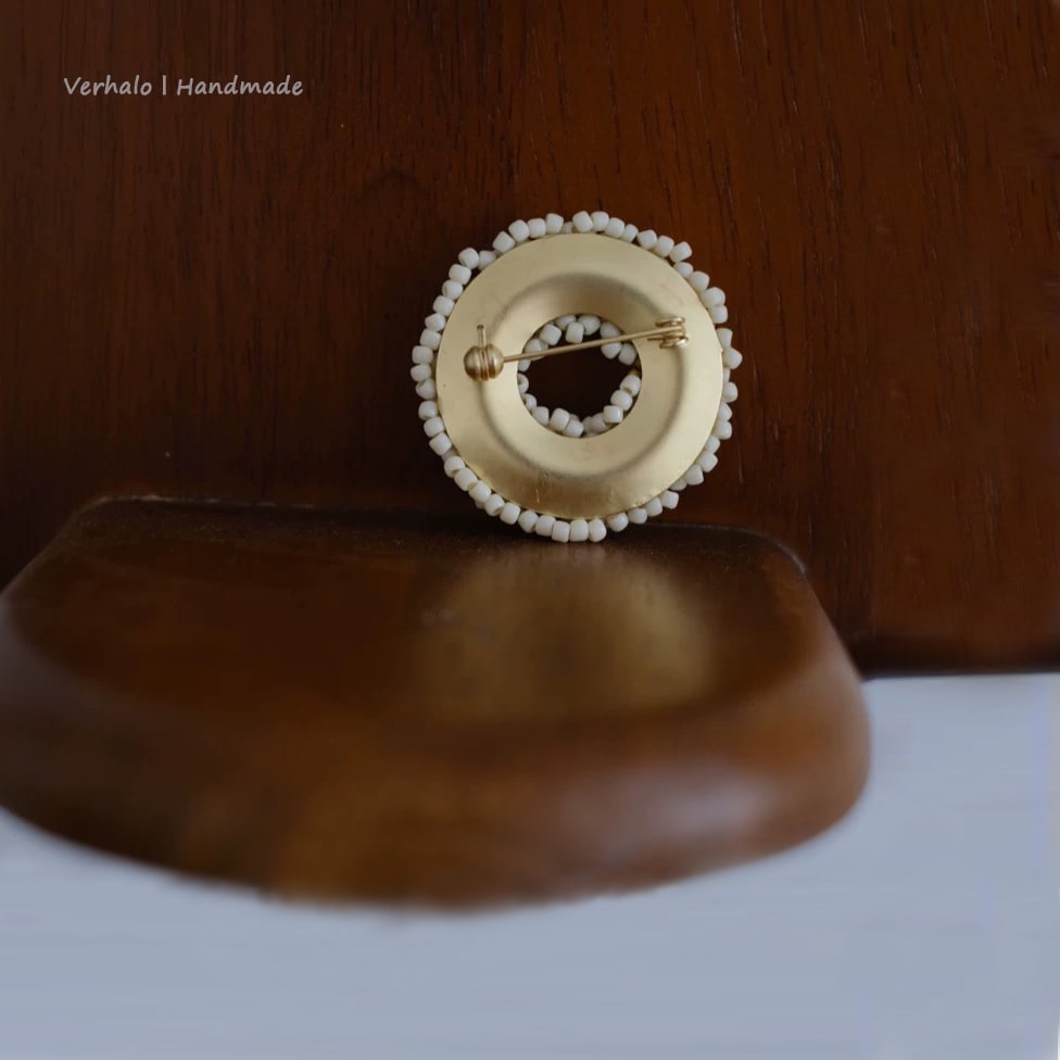 Handmade brooch with beaded design on a wooden surface