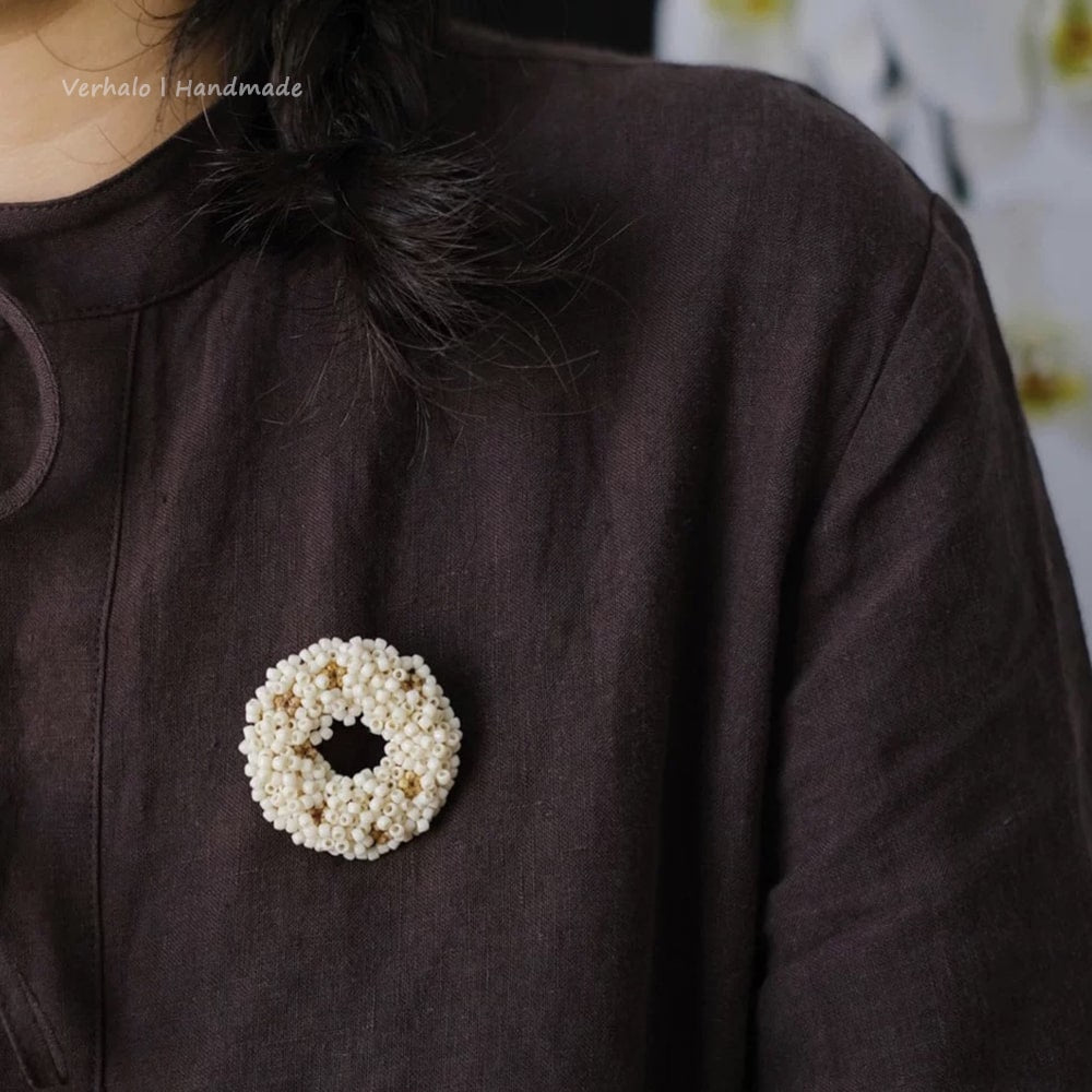 Close-up of a brown garment with a decorative brooch featuring a circular design.