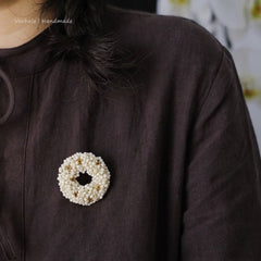 Close-up of a brown garment with a decorative brooch featuring a circular design.