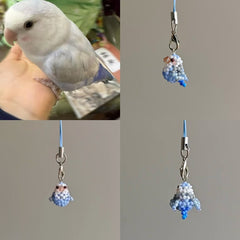 Small bird perched on a hand with two beaded charms resembling the bird on a gray background.