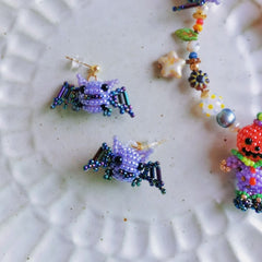 Colorful beaded Halloween spider earrings on a textured white surface - verhalo custom jewelry