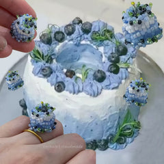 handmade cake ring from verhalo-Decorative earrings resembling a cake with blueberries and cream, held by hands.