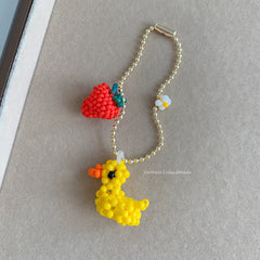 Handmade keychain with a yellow duck and red strawberry on a gray background