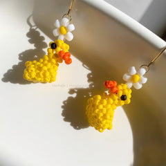 Yellow duck-shaped earrings with flowers on a white background