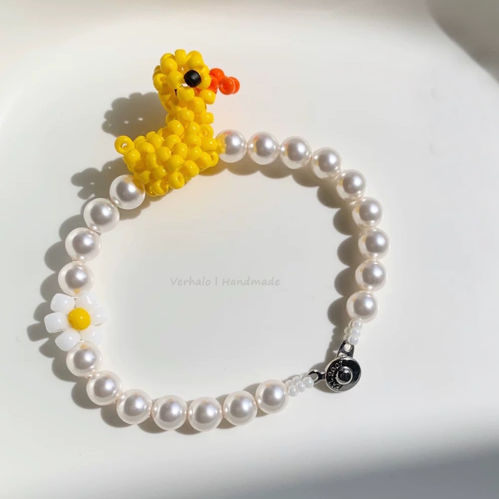 Pearl bracelet with a yellow beaded duck charm on a white background
