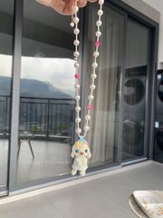 Holland Lop Necklace with beads and a small figurine held in front of a glass door.