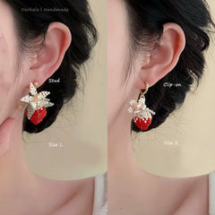 Two strawberry-shaped earrings, one stud and one clip-on, on a person's ears with labels indicating size and type.